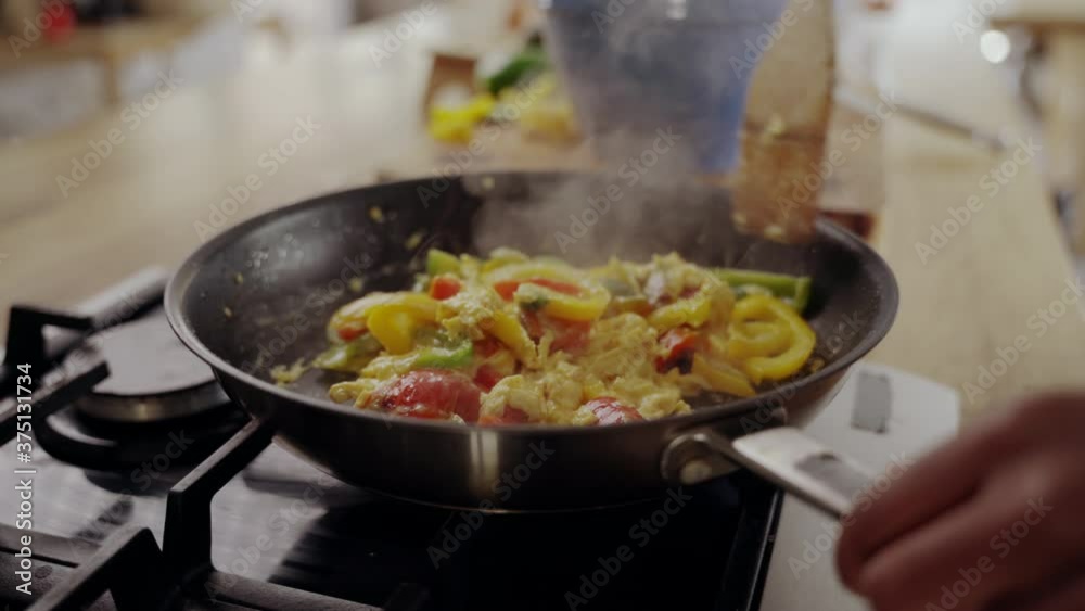 Close-up of woman's hand cooking food in frying pan over the gas stove