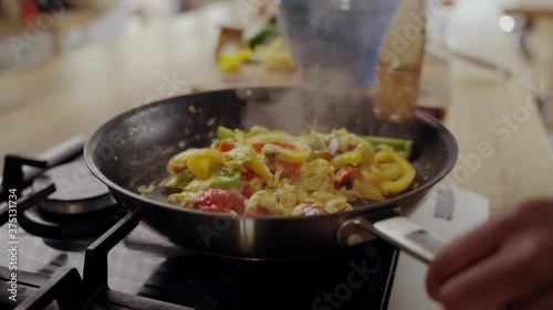 Close-up of woman's hand cooking food in frying pan over the gas stove