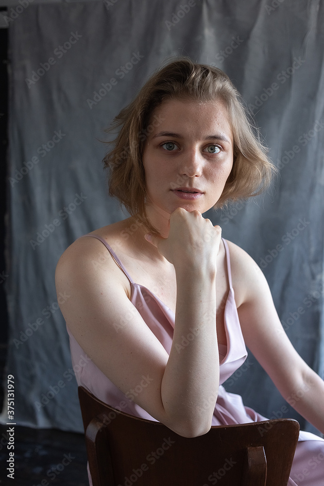 portrait of young caucasian woman with short hair posing in pink suit, sitting on chair in front of fabric background. model tests of pretty girl in blouse. attractive female poses portrait of young caucasian woman with short hair posing in pink suit, sitting on chair in front of fabric background. model tests of pretty girl in blouse. attractive female poses
