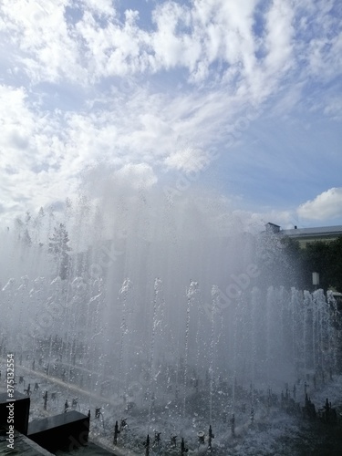 many beautiful fountains behind a granite fence on a Sunny summer day against a blue sky with clouds