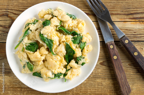 scrambled eggs with spinach in a white plate.