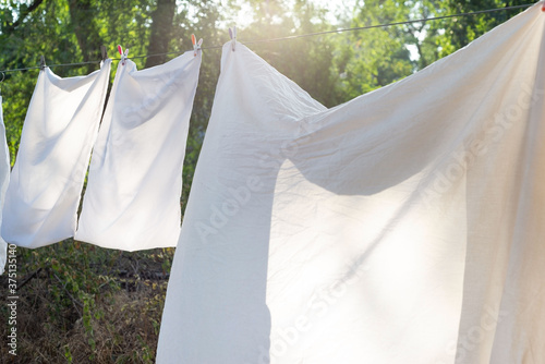 white bedding, clothesline drying, hanging outside. Against the background of the rays of the setting sun