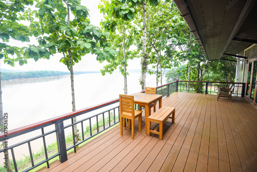 Wooden table and chairs on balcony and nature green tree forest / balcony view river terrace house