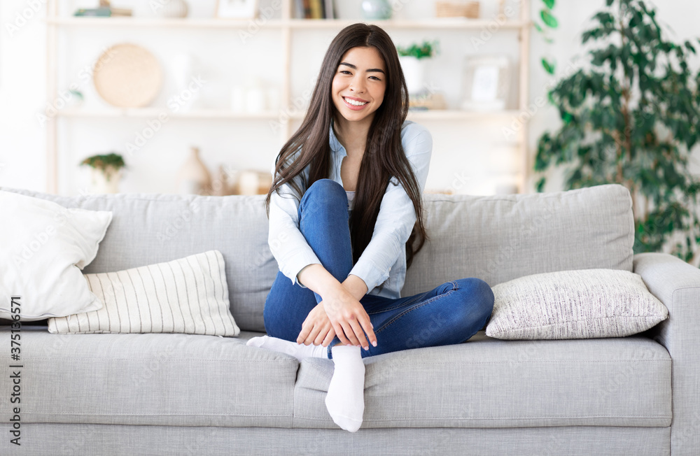 Portrait of relaxed smiling korean girl posing on sofa at home Portrait of relaxed smiling korean girl posing on sofa at home