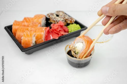 take away sushi in plastic containers, philadelphia rolls and unagi maki, soy sauce, pink ginger, wasabi, sushi delivery concept