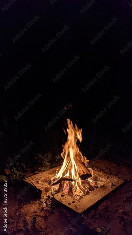 Заголовок: Camp fire in the night. Bonfire. Flame and fire sparks on dark background. Black copy space.