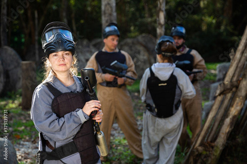 Portrait of girl in full gear posing with shooting gun at paintball shooting range