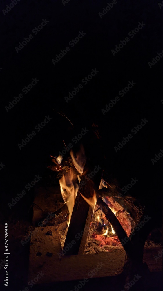 Заголовок: Camp fire in the night. Bonfire. Flame and fire sparks on dark background. Black copy space.