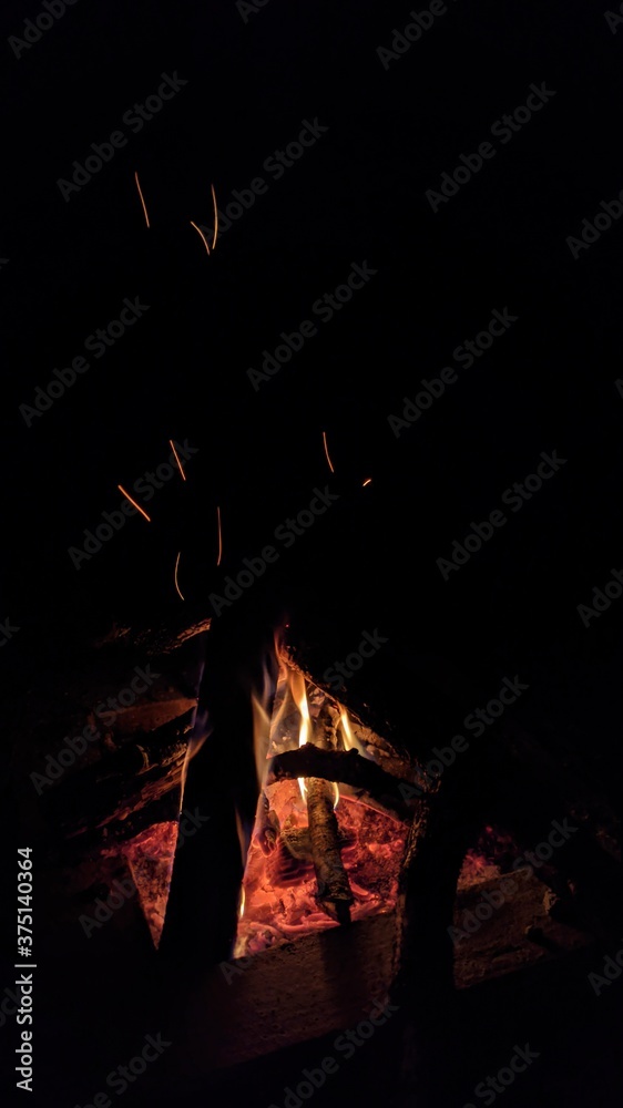 Заголовок: Camp fire in the night. Bonfire. Flame and fire sparks on dark background. Black copy space.