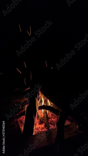 Obraz na płótnie Заголовок: Camp fire in the night. Bonfire. Flame and fire sparks on dark background. Black copy space.
w salonie