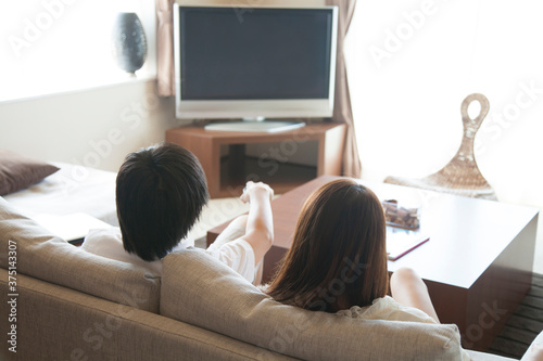 ソファに座ってテレビを観るカップル
