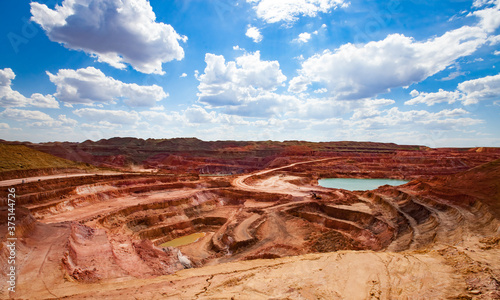 Aluminium ore quarry and blue lake in bauxite clay mine. Open cast (open-cut) mining. Panorama view. Blue sky with clouds in summer day. photo