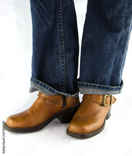 People wearing blue jeans, brown leather boots standing on white background.