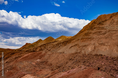 Bauxite open cast  open cut  mining. Color aluminium ore quarry. Big yellow piles of empty rocks.  Slag heaps . On blue sky with clouds.