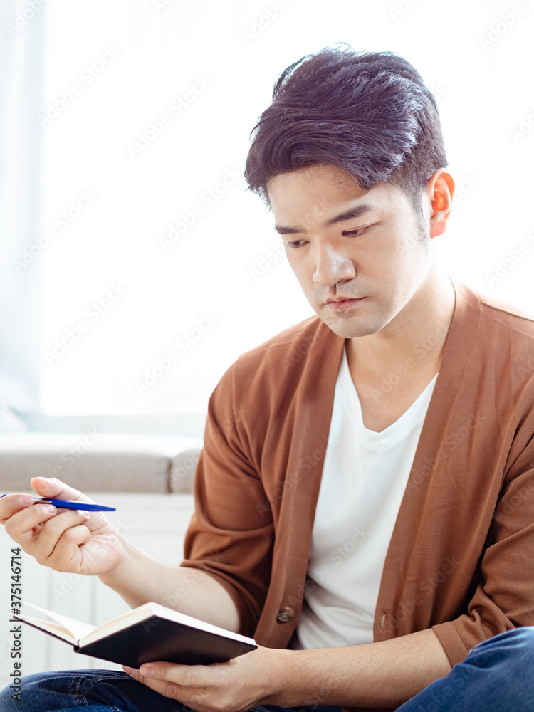 Cross-legged young asian man writing in notebook. Cross-legged young asian man writing in notebook.