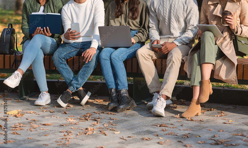 Group of students sitting on bench in park and studying Group of students sitting on bench in park and studying