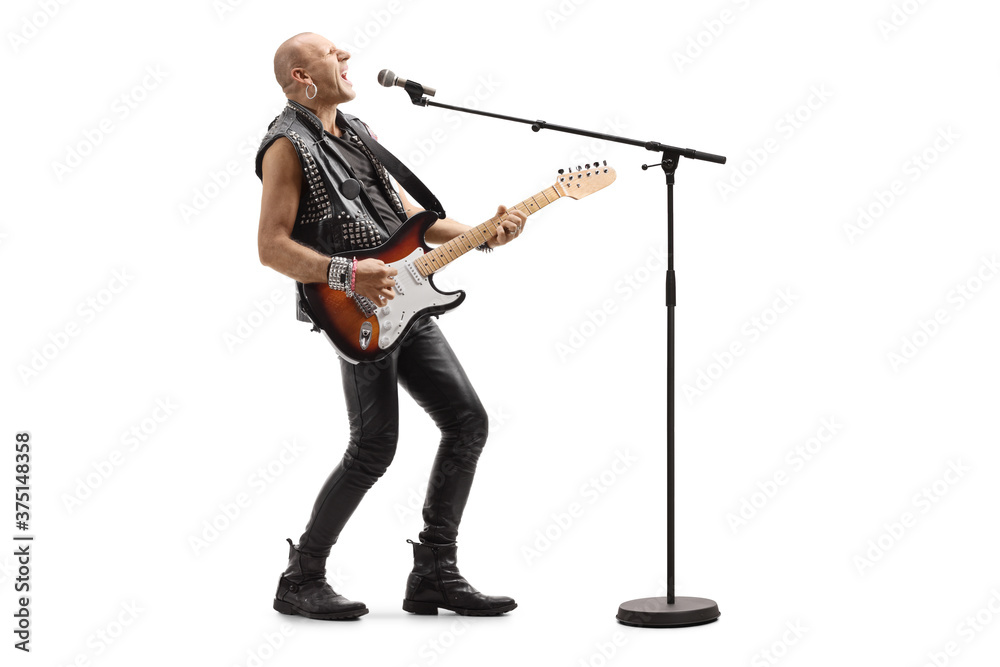 Bald punk rocker singing on a microphone and playing a guitar
