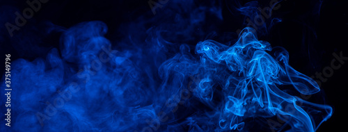 Conceptual image of blue color smoke isolated on dark black background, Halloween design element concept.