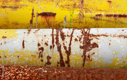 Detail of a weathered and rusted bright yellow steel pipes makes a banded abstract industrial background