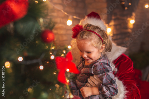 Little girl and Santa decorating Christmas tree