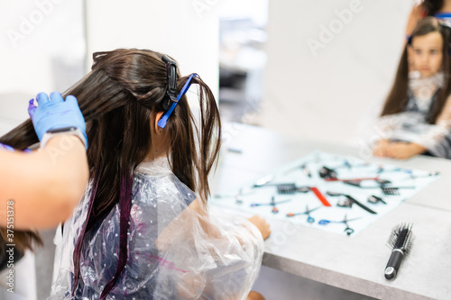 Картината върху платно little girl dyes her hair purple in a hairdressing salon
