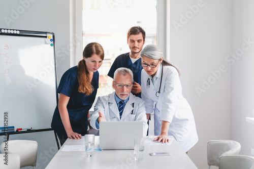 Team of medical professionals looking in laptop discussing during meeting in boardroom