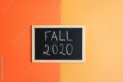 Fall 2020 concept: blackboard with phrase "Fall 2020" on orange background. Autumn season flat lay