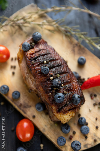 Goose breast Christmas roast with blueberries, tomatoes, red peppers and rosemary served on a wooden board photo