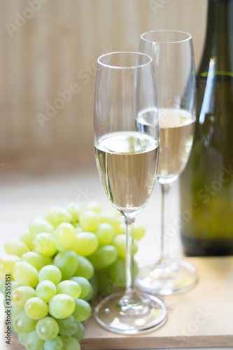 Two glasses with sparkling wine and grapes on light wooden background. Close-up. Selective focus.