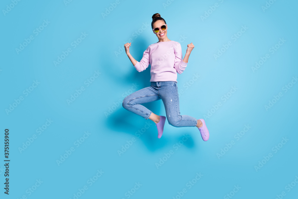 Full size photo of cheerful energetic girl jump celebrate luck discounts lottery win raise fists wear lilac violet sweater sneakers spectacles isolated over blue color background