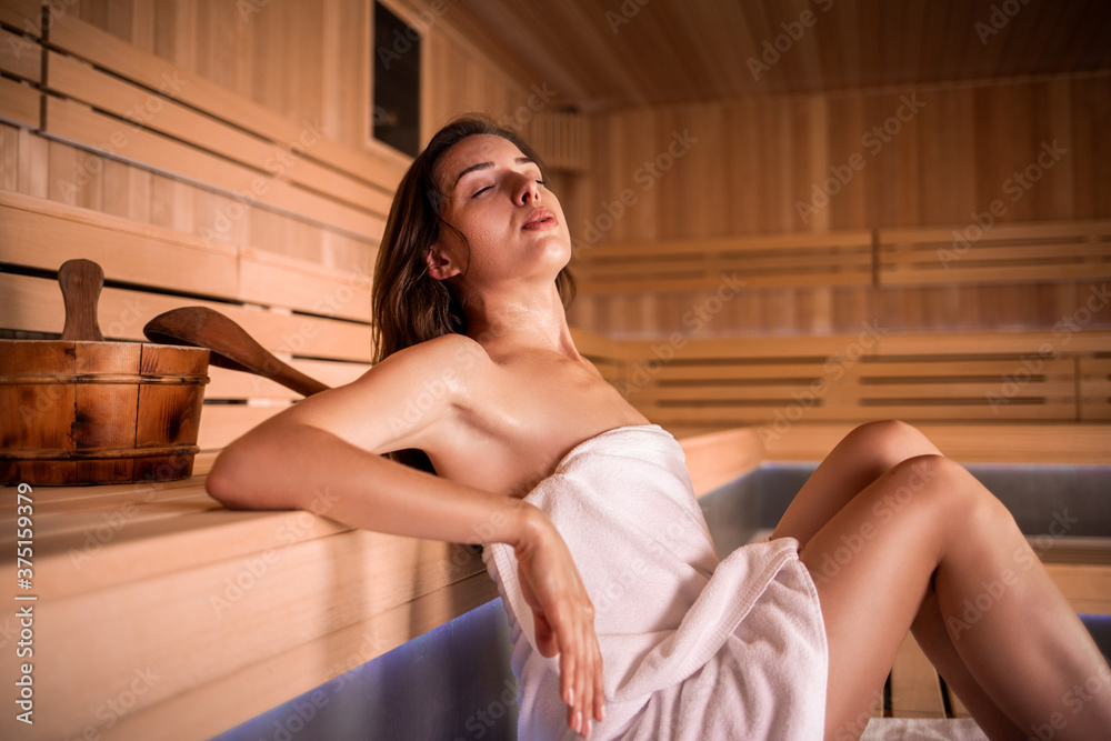 Beautiful woman in white towel relaxing in sauna Beautiful woman in white towel relaxing in sauna