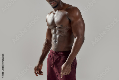 Canvas Print Cropped shot of muscular african american man showing his naked torso while posing shirtless isolated over grey background