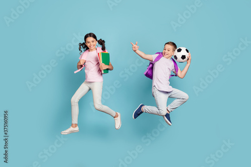 Full length body size view of his he her she attractive small little cheerful friends friendship jumping having fun playing football cup goal free time isolated blue pastel color background