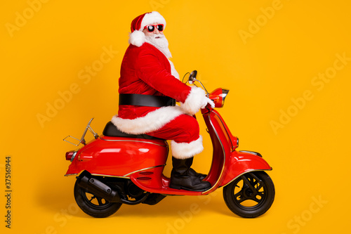 Profile side view of his he nice funny hipster white-haired Santa riding motor bike way road destination travel trip rout Eve Noel isolated bright vivid shine vibrant yellow color background