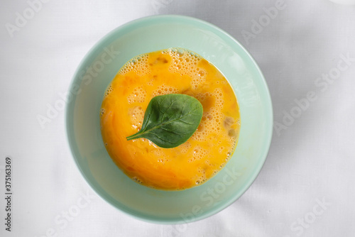 The process of making tasty egg omelet with green spinach leaves for breakfast on a white background. Top view. Idea recipe for a healthy diet food. Easy to cook. Protein food for vegetarian.