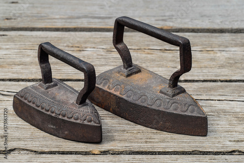 Old antique irons on vintage wooden background