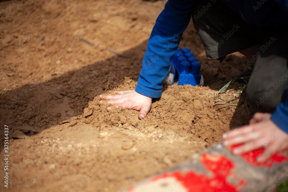 The child plays with his hands in the sand. The child plays with his hands in the sand.