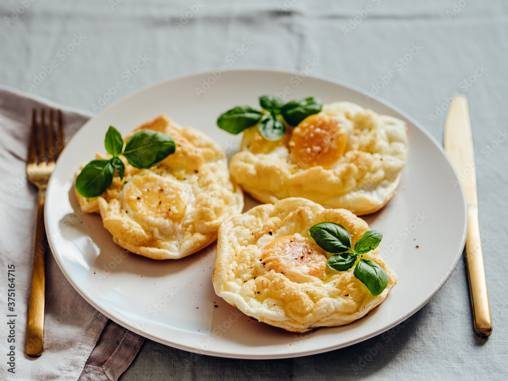 Fluffy Cloud Eggs. Trendy food - oven bake scrambled eggs with whipped egg white and whole yolk on plate Fluffy Cloud Eggs. Trendy food - oven bake scrambled eggs with whipped egg white and whole yolk on plate
