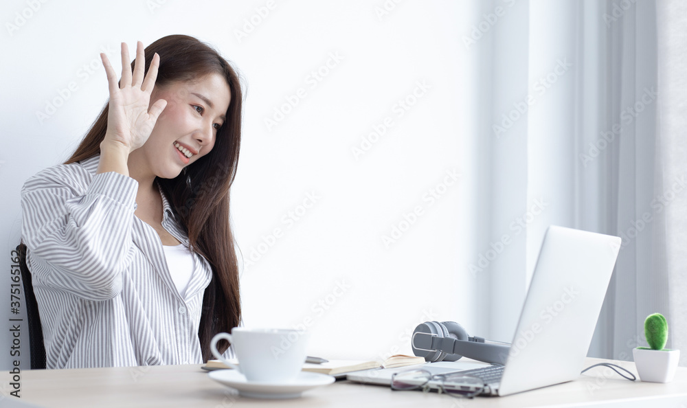 Young Asian woman works on paperwork in her own home online. Young Asian woman works on paperwork in her own home online.