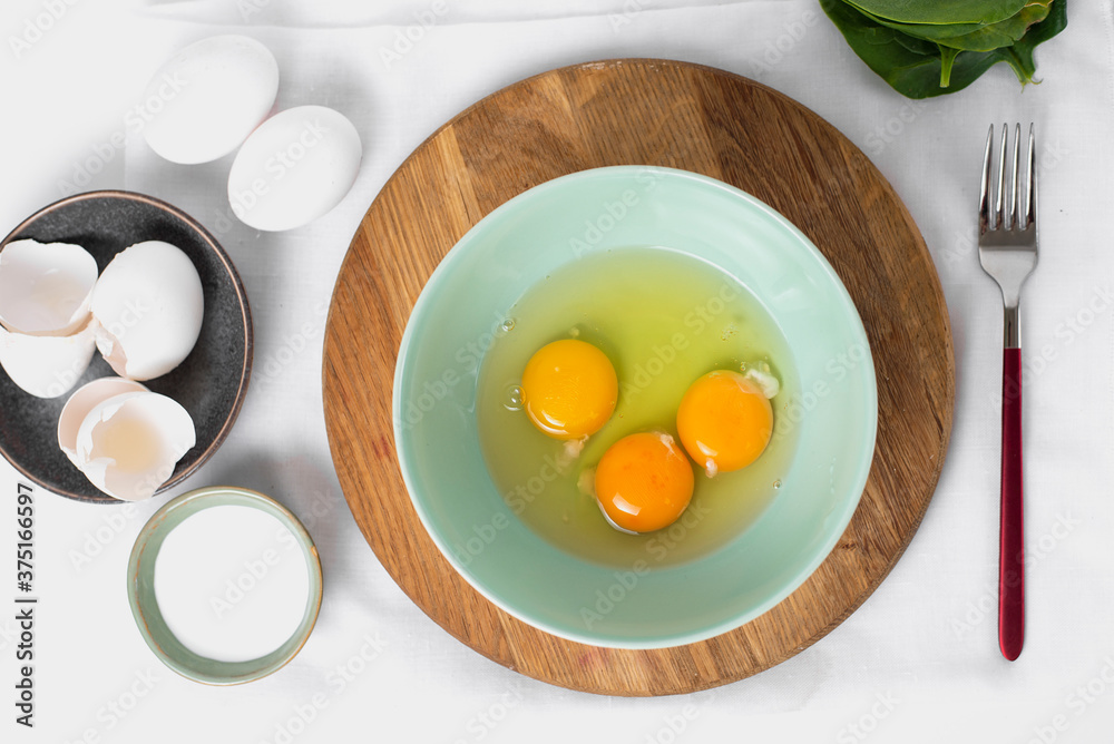 The process whisking egg yolks, making tasty egg omelet with green spinach for breakfast on white background. Idea recipe for a healthy diet food. Protein food for a vegetarian. Easy to cook. The process whisking egg yolks, making tasty egg omelet with green spinach for breakfast on white background. Idea recipe for a healthy diet food. Protein food for a vegetarian. Easy to cook.
