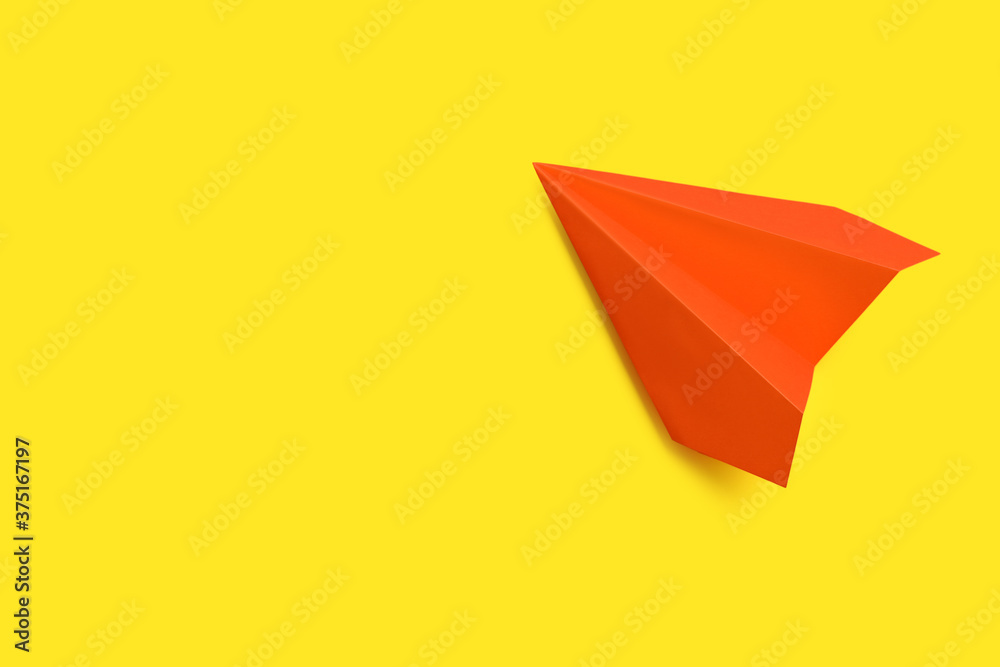 Orange paper plane on yellow background, top view. Space for text Orange paper plane on yellow background, top view. Space for text
