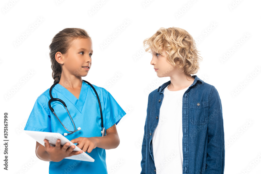 kid in costume of doctor using digital tablet near curly boy isolated on white kid in costume of doctor using digital tablet near curly boy isolated on white