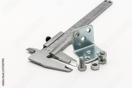measuring tool caliper and bolts with nuts on a white background