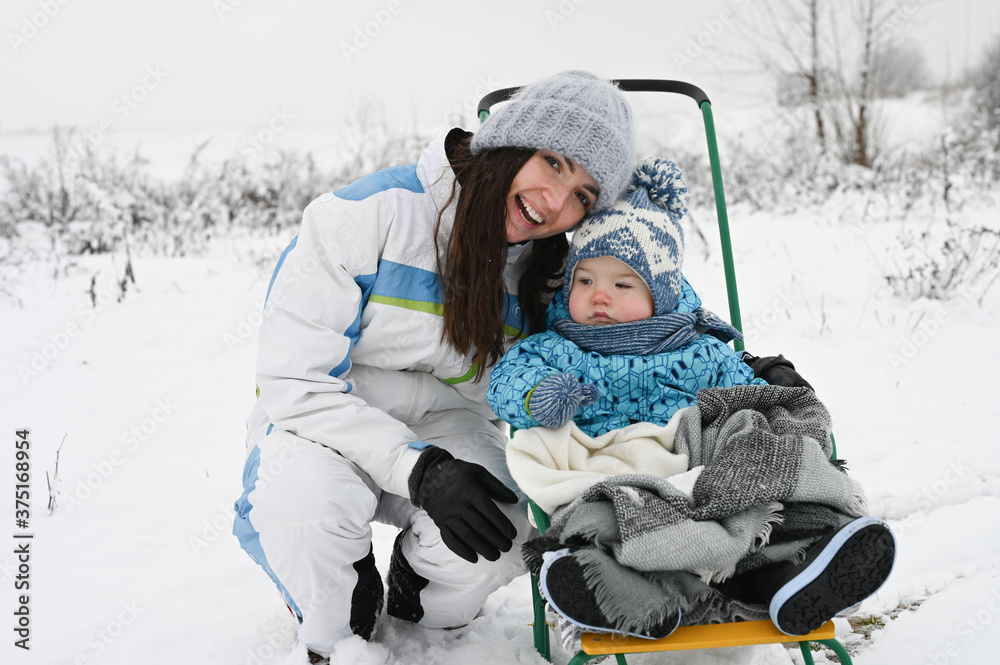portrait of a mother with a child on a sled