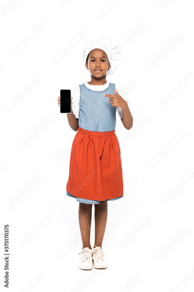 african american kid dressed in costume of chef pointing with finger at smartphone with blank screen isolated on white african american kid dressed in costume of chef pointing with finger at smartphone with blank screen isolated on white
