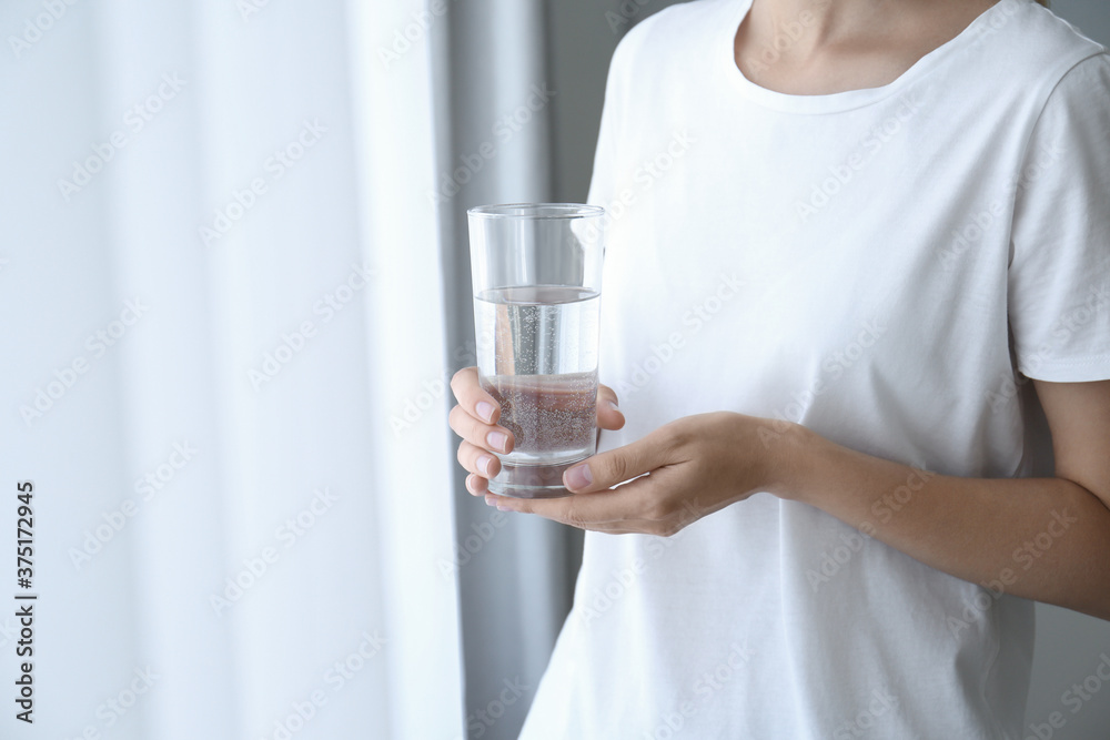Woman holding glass of water near window at home, closeup Woman holding glass of water near window at home, closeup