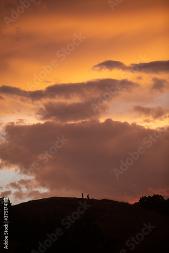 Couple of people on a hill at sunset
