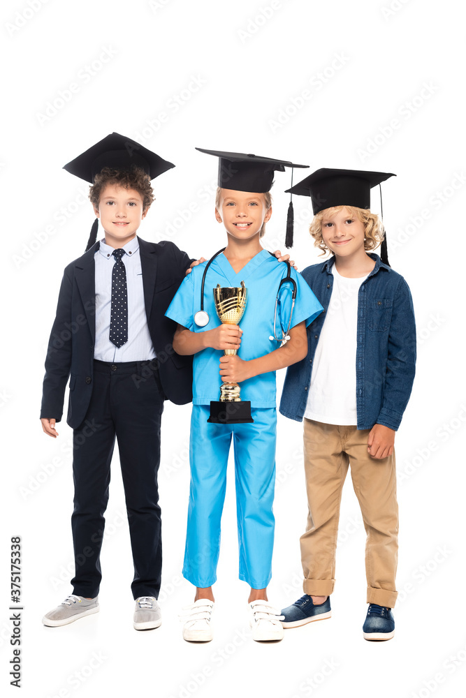 children in graduation caps dressed in costumes of different professions holding trophy isolated on white children in graduation caps dressed in costumes of different professions holding trophy isolated on white