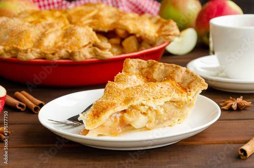 Εκτύπωση καμβά Slice of classic American apple pie with cinnamon on a white plate on a dark wooden background