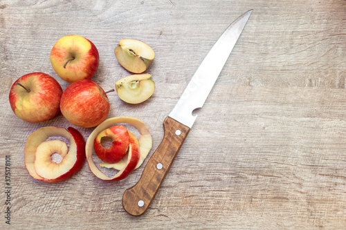 Red ripe cutted apples and peel with knife on wooden table. Fresh fruit background with copy space for text, cooking concept photo